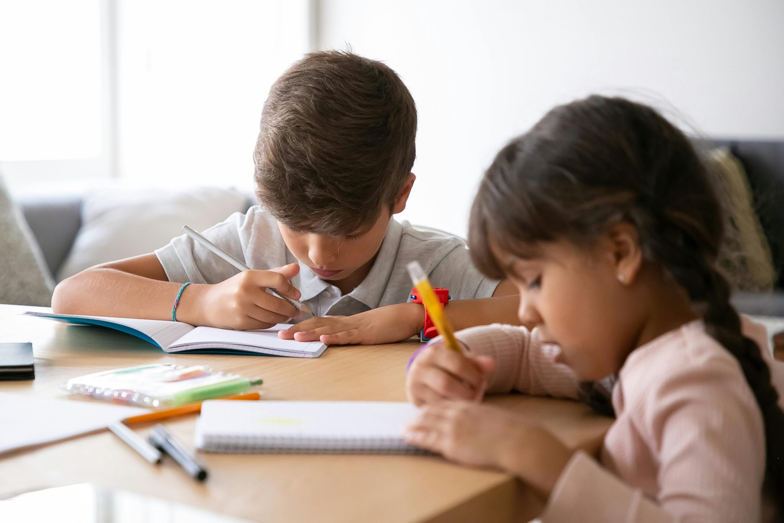Two children studying together at home, focused on their schoolwork.